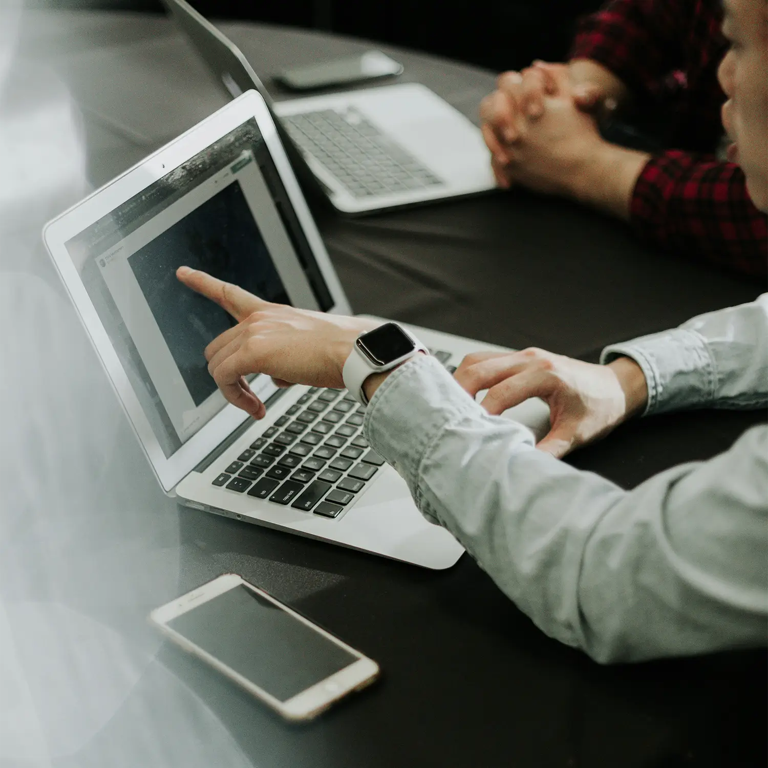 Close up of a man pointing at a laptop screen in an office.