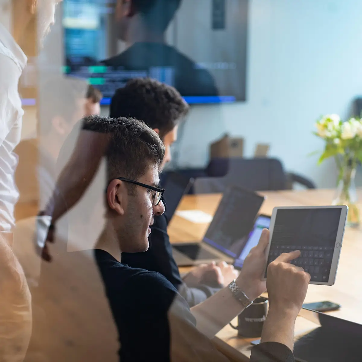 Man in a meeting room typing in on an ipad.